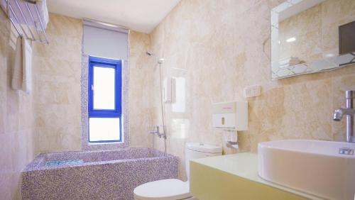 y baño con lavabo, aseo y bañera. en Easy Stay B&B, en Magong