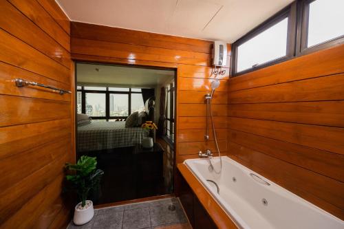 a bathroom with wooden walls and a tub and a bed at MN residence at Thonglor in Bangkok