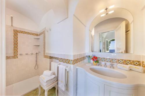 bagno bianco con lavandino e specchio di Casa Mercè Positano a Positano