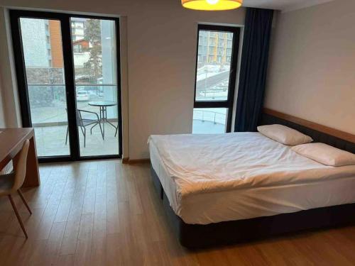 a bedroom with a bed and a table and windows at Orbi Palace Bakuriani Apartment in Bakuriani