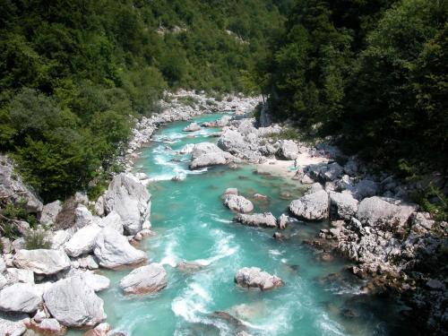 a river with rocks and blue water and trees at Chalet and Apartment Žonir with SAUNA in Kobarid