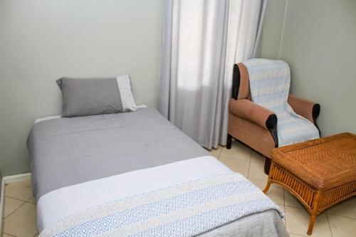 a small bedroom with a bed and a chair at House Samaika in Maun