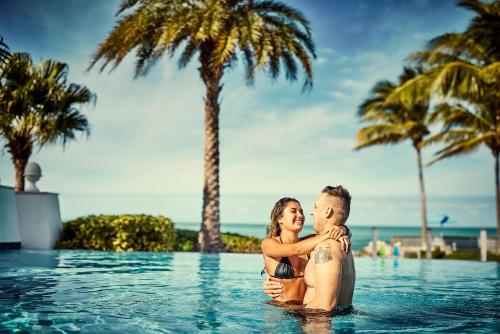 un hombre y una mujer parados en la piscina de un resort en Courtyard by Marriott Faro Blanco Resort, en Marathon