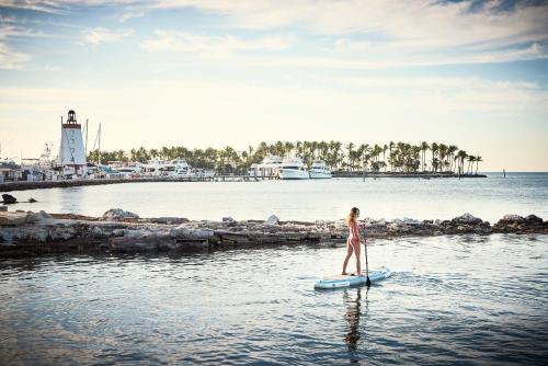 a woman in a bikini standing on a paddle board in the water at Courtyard by Marriott Faro Blanco Resort in Marathon