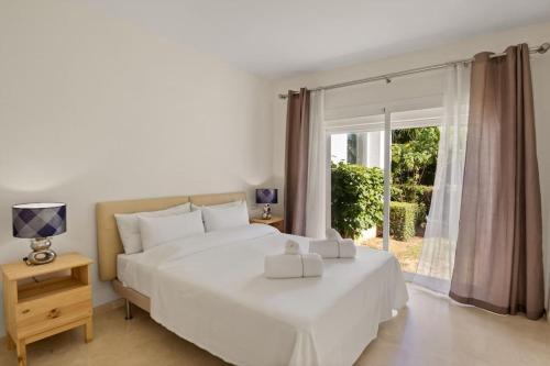 ein weißes Schlafzimmer mit einem großen Bett und einem Fenster in der Unterkunft Alcazaba Lagoon modern flat Ref M14 in Estepona