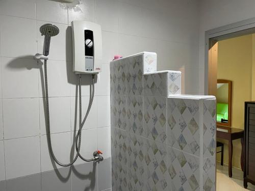 a shower in a bathroom with a blow dryer on the wall at Nawaporn Place in Phuket Town