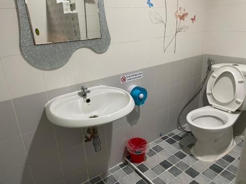 a bathroom with a sink and a toilet and a mirror at Nawaporn Place in Phuket Town