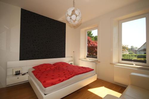 1 Schlafzimmer mit einem roten Bett und 2 Fenstern in der Unterkunft Villa Rosengarten auf der Sonneninsel Fehmarn in Fehmarn