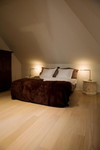 a bedroom with a large bed with two lamps at vakantiehuis ter poele in Avelgem