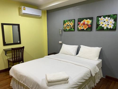 a bedroom with a large white bed with three paintings on the wall at Nawaporn Place in Phuket Town