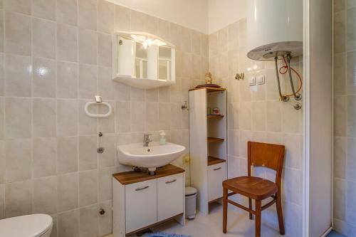 a bathroom with a sink and a toilet and a chair at Ivka 2 in Mali Lošinj