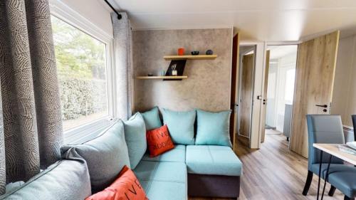 a living room with a blue couch and a window at Camping Officiel Siblu Mer et Soleil in Les Sables Vignier