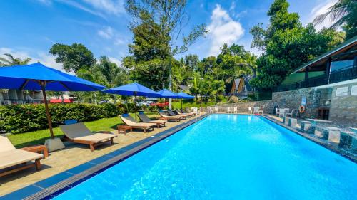 a swimming pool with lounge chairs and umbrellas at Royal Classic Resort in Kandy