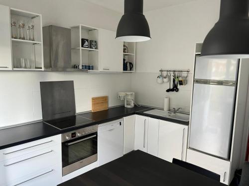 eine Küche mit weißen Schränken und schwarzen Arbeitsplatten in der Unterkunft Insel Hus in Fehmarn