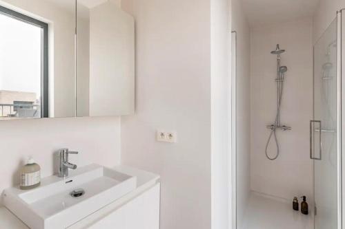 a white bathroom with a sink and a shower at New apartment with big terrace and great views! in Leuven