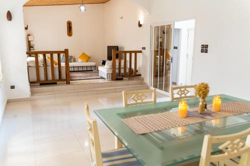 uma sala de jantar com uma mesa de vidro e cadeiras em Spacious and cozy beachfront villa em Grand-Popo