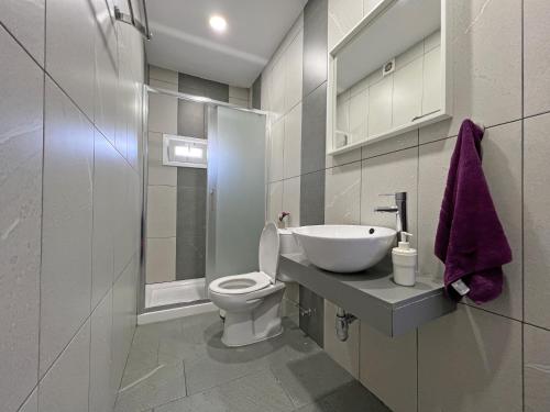a white bathroom with a toilet and a sink at Apollo Rooms by Albert's Apartment in Larnaca