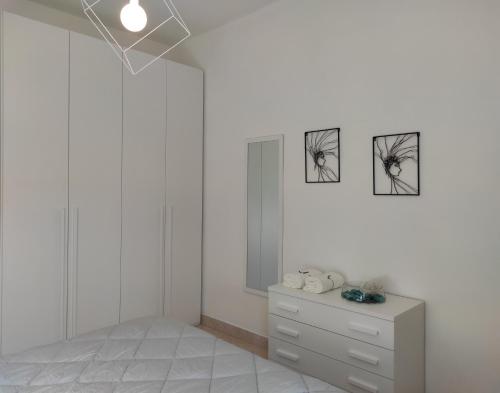 une chambre blanche avec une commode et deux photos sur le mur dans l'établissement Casa Crispi, à Chioggia