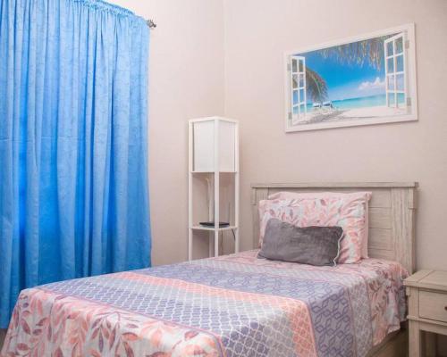 Gorgeous 2-Bed Apartment 3 in St Johns cosy في Belmont: غرفة نوم بسرير والستائر الزرقاء ونافذة