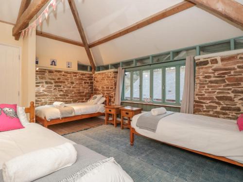Cette chambre comprend 2 lits et un mur en briques. dans l'établissement 1 Alston Farm Cottages, à Brixham