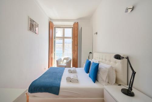 a white bedroom with a bed with blue pillows at Casa Portuguesa Chiado in Lisbon