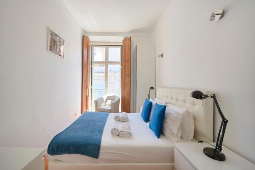 リスボンにあるCasa Portuguesa Chiadoの白いベッドルーム(青い枕のベッド付)