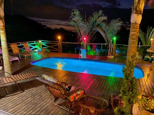 a swimming pool with lights on a deck at night at Bangalô house - Praia do Rosa SC in Praia do Rosa