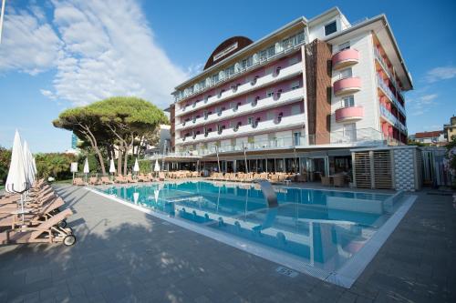 a hotel with a swimming pool in front of a building at Hotel Cesare Augustus in Lido di Jesolo