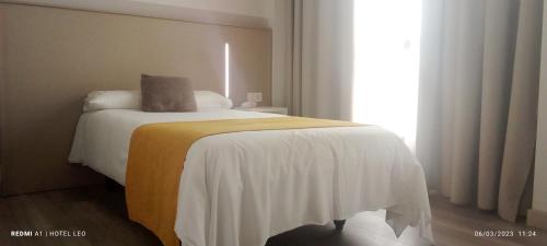 a bedroom with a bed with white sheets and a window at Hotel Leo in Monesterio