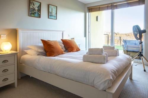 a bedroom with a large white bed with orange pillows at Clearwater 31, The Lakehouse in Somerford Keynes