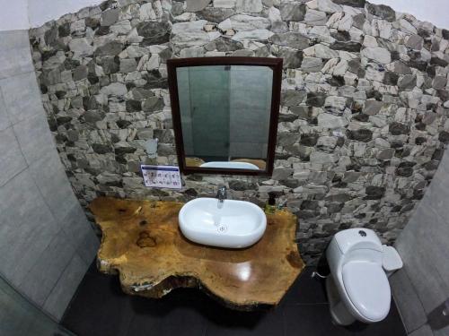 a bathroom with a sink and a mirror on a stone wall at EcoHostal Rio Piedra in El Zaino