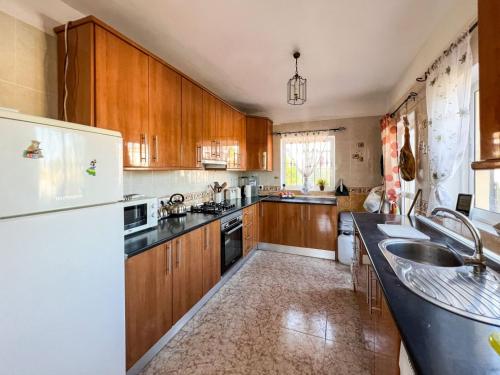 uma cozinha com armários de madeira e um frigorífico branco em Villa Bravo em Partaloa