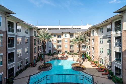 an apartment courtyard with a swimming pool and palm trees at A Touch of Class in Houston