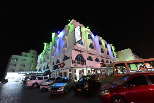 a large building with cars parked in front of it at Al Bahjah Hotel in Seeb