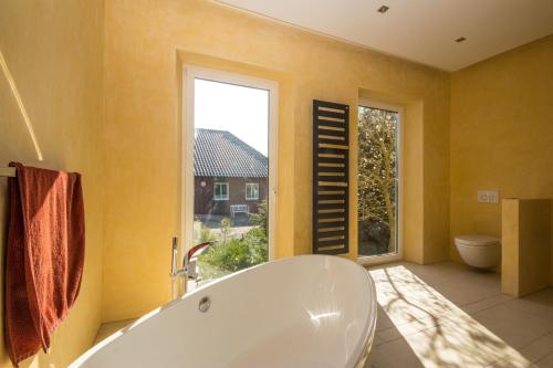 ein großes Bad mit einer Badewanne und einem Fenster in der Unterkunft Villa Rosengarten auf der Sonneninsel Fehmarn in Fehmarn