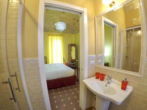baño con lavabo, espejo y cama en Palazzo Florio Boutique Residence, en Vasto