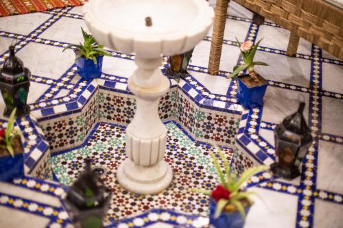 a white candle on a mosaic floor with plants at Medina Sky in Fez