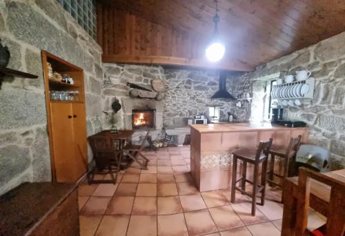 a stone kitchen with a table and chairs and a fireplace at Casa do Crego in Vilaboa