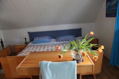 Dom na Warmii في ليدزبارك فارنيتسكي: غرفة نوم بسرير وطاولة مع إناء من الزهور