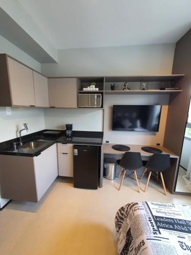 a kitchen with a sink and a table and a tv at Studio Perdizes Allianz in São Paulo