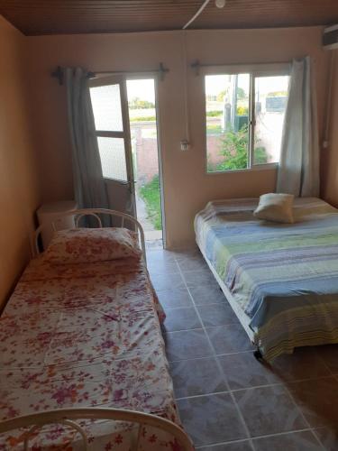 1 dormitorio con 2 camas y 2 ventanas en Alojamiento en Tacuarembó, en Tacuarembó