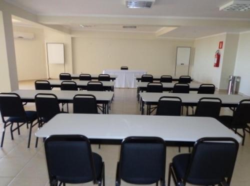 a room with tables and chairs in a classroom at Class Hotel Passos Rio Grande Portal da Canastra in Passos