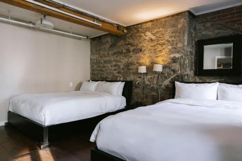 - 2 lits dans une chambre avec un mur en briques dans l'établissement Lofts du Vieux-Port by Gray Collection, à Montréal