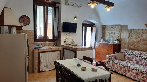 a kitchen and living room with a table and a couch at Dammuso Donna Giovanna in Scicli