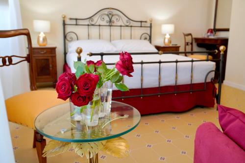 ein Schlafzimmer mit einem Bett und einem Glastisch mit Rosen in der Unterkunft Palazzo Florio Boutique Residence in Vasto