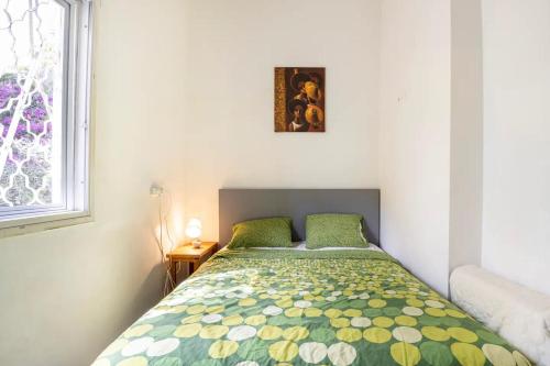 een slaapkamer met een bed met een groen en geel dekbed bij People LOVE this home! in Haifa