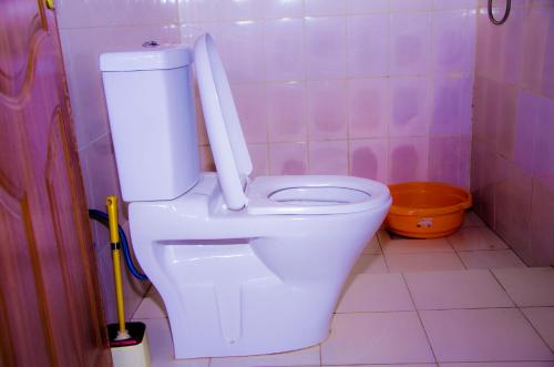 - des toilettes blanches dans une salle de bains carrelée de rose dans l'établissement PARADOR MOTEL KIGALI, à Kigali