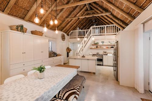 a kitchen with white cabinets and a table in a room at Bliss on the Bay in Struisbaai