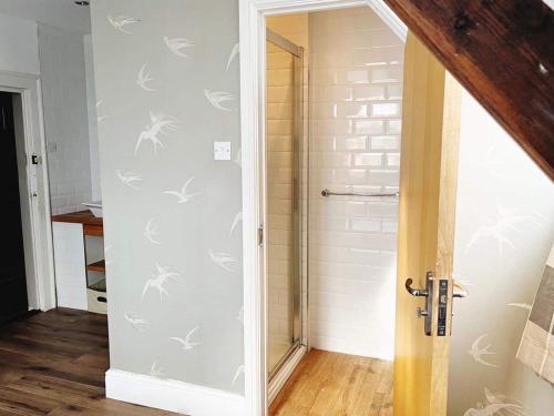 a bathroom with a glass door with white birds on the wall at 4 bed loft apartment overlooking historic town in Trowbridge