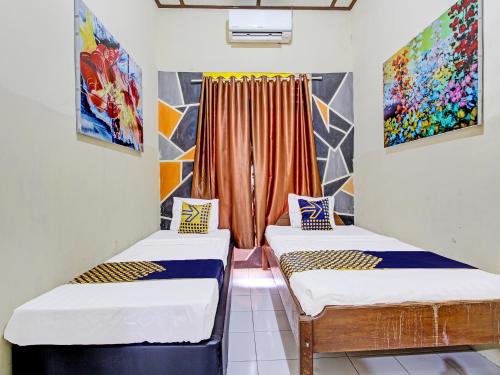 duas camas num quarto com pinturas na parede em SPOT ON 92319 White House Syariah em Yogyakarta
